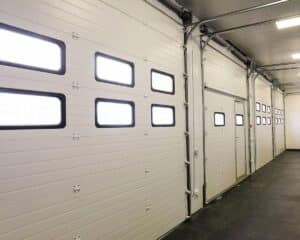 Row of overhead sectional doors in a multi-seat car garage. Inside view.
