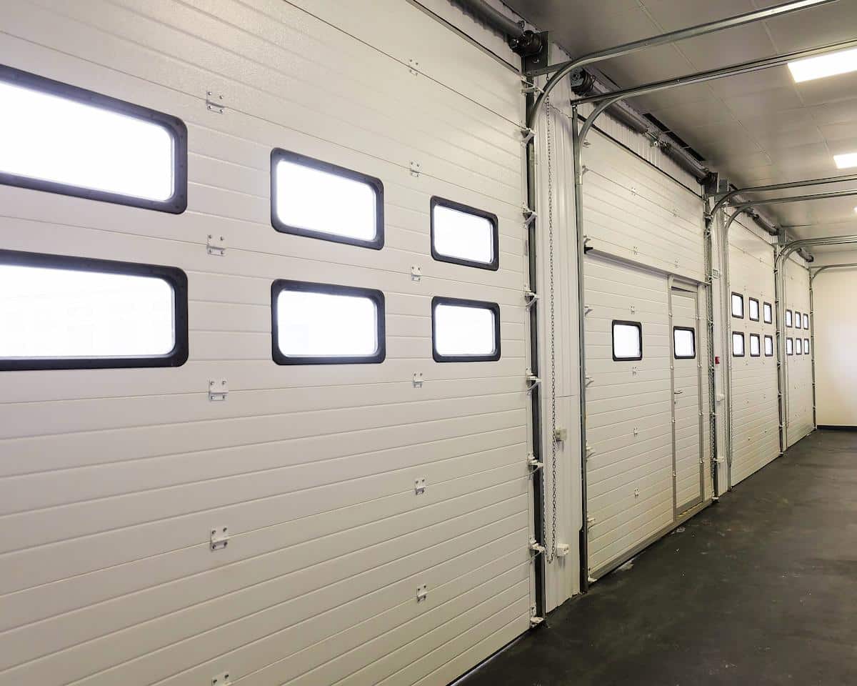 Row of overhead sectional doors in a multi-seat car garage. Inside view.
